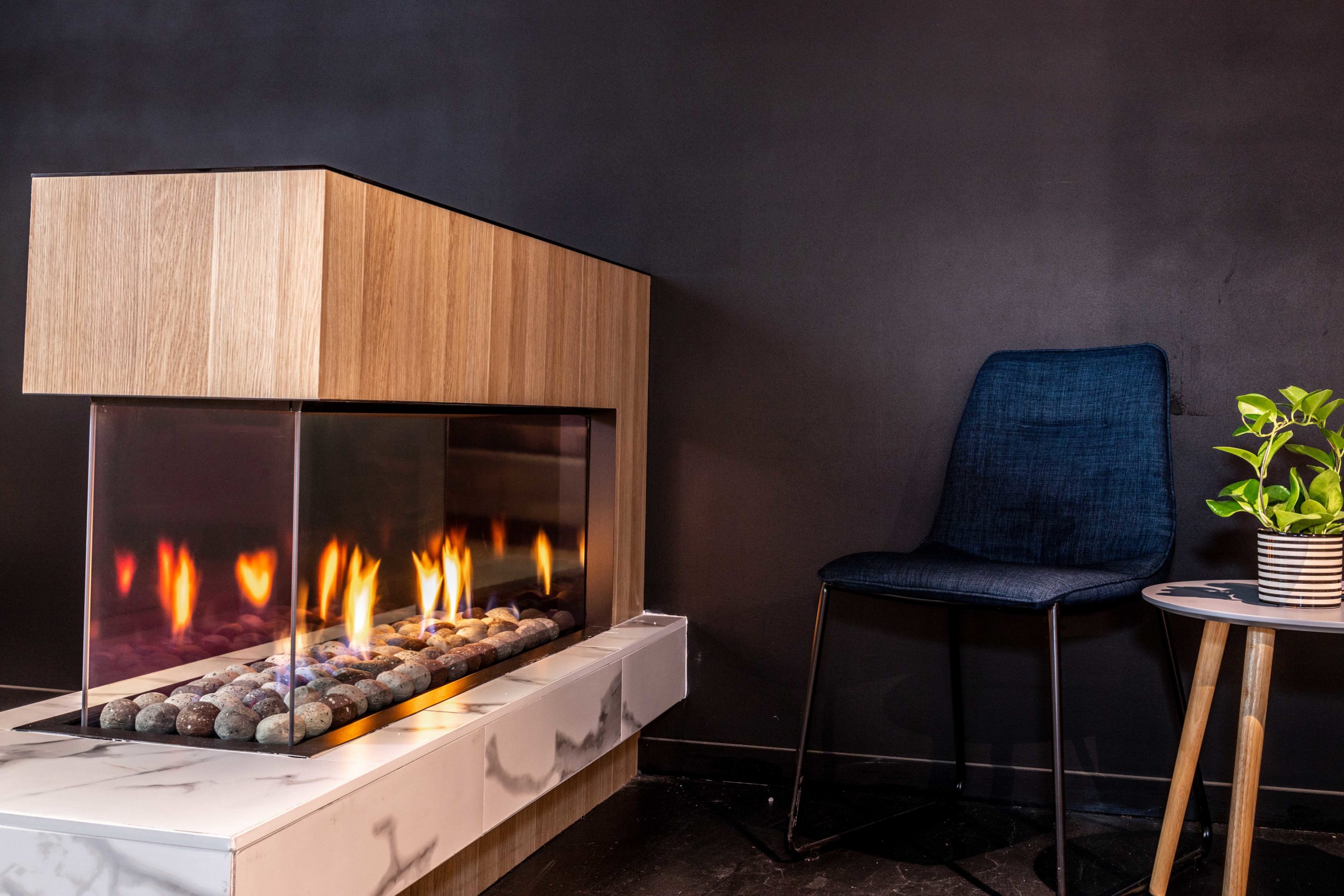 Chimney, interior wall and mantel gas log fires featured in sleek and modern stone-finished flooring on display.